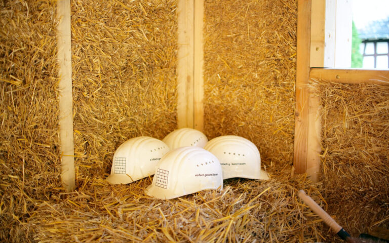 Picture of helmets with LORENZ inscription, stored in a straw house made of LORENZ wooden straw walls