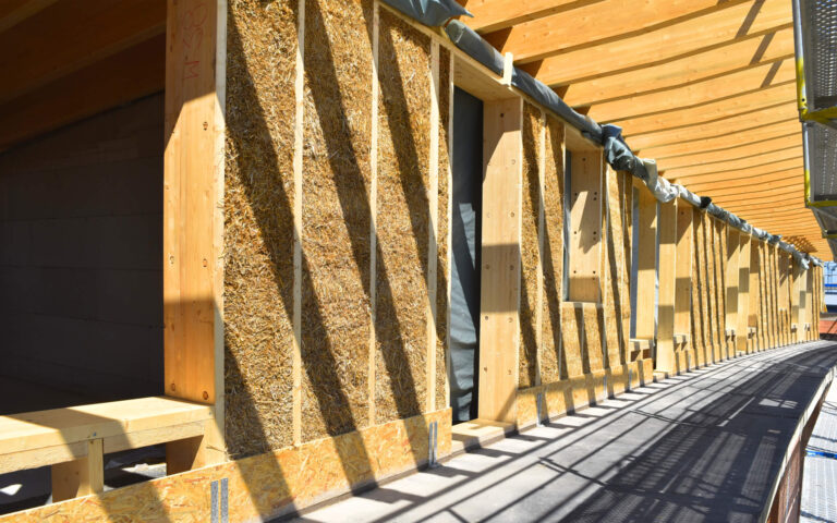 Facade view of the multi-generation hybrid building in Kassel with shiny golden straw surface with LORENZ DD mounting systems made of wood and straw for insulation and construction