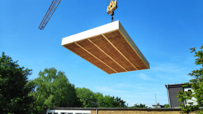 Image of a straw insulation module moved by crane for the serial and large-scale, energy-efficient renovation of the largest municipal reference project with straw insulation in Oberhausen