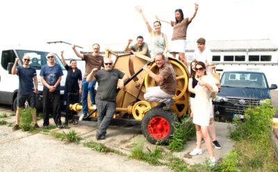 Group photo of the LORENZ-einfach.gesund.bauen. team on an old agricultural straw baler